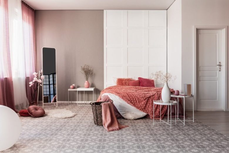 Amaranth pillow and dirty orange bedding on king size bed in fashionable bedroom interior