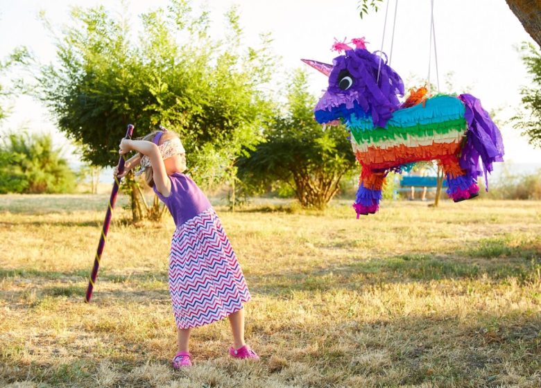 Young girl at an outdoor party hitting a pinata