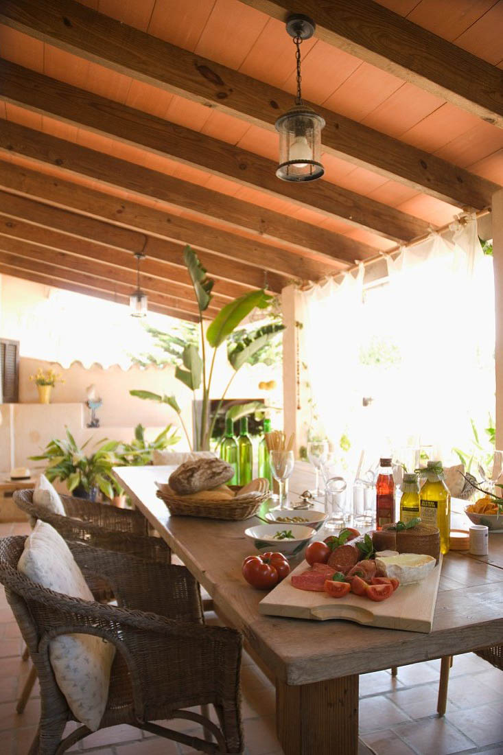 Mediterrane Brotzeit auf der Veranda &#8211; gedeckter Terrassentisch unter Holzdach