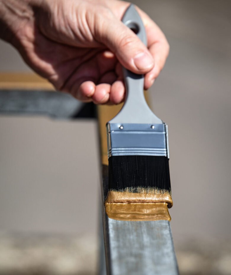 man is painting a metal railing with copper varnish