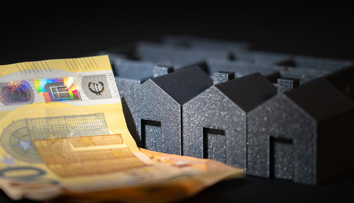 Close-up of black miniature houses with Euro notes, representing real estate investment and savings. Close-up of black miniature houses with Euro notes, representing real estate investment and savings.