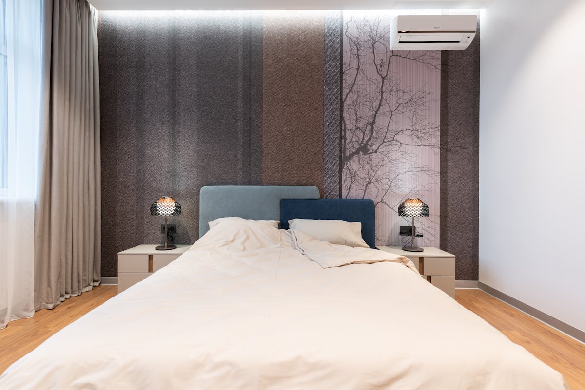 Interior of modern bright room with bed near table with lamp near wall and window with curtains and wooden floor Interior of modern bright room with bed near table with lamp near wall and window with curtains and wooden floor
