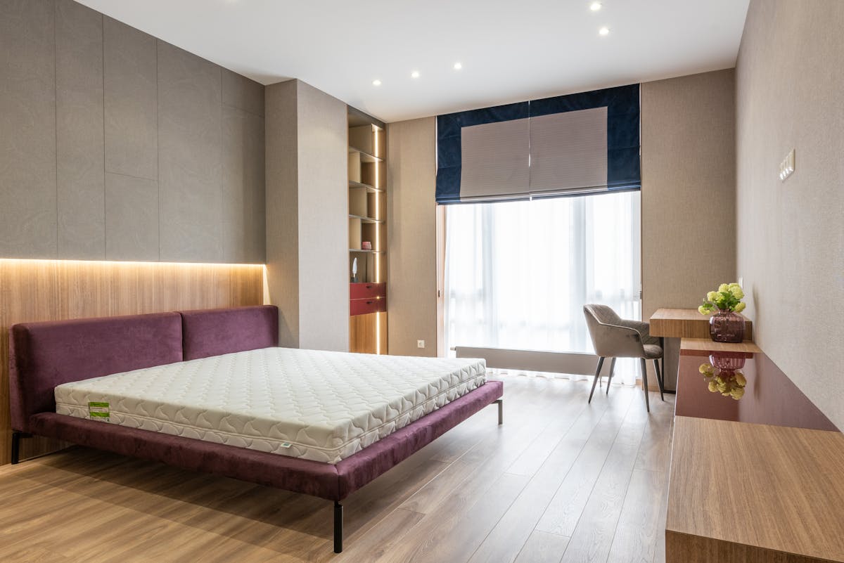 Contemporary interior design of modern bedroom with comfortable bed without sheets and vanity table near window Contemporary interior design of modern bedroom with comfortable bed without sheets and vanity table near window