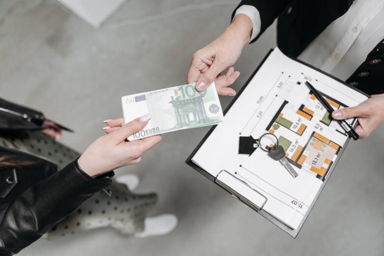 Close-up of a real estate transaction with euro bill, keys, and floor plan.