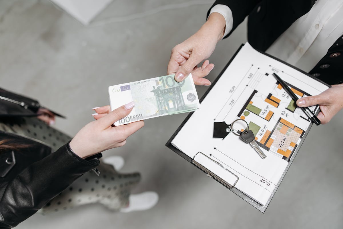 Close-up of a real estate transaction with euro bill, keys, and floor plan. Close-up of a real estate transaction with euro bill, keys, and floor plan.