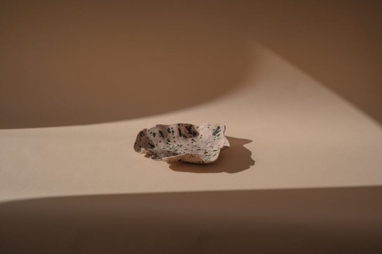 Artistic ceramic plate in a minimalist setting with dramatic lighting and shadows.