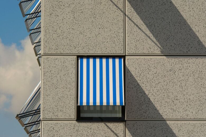 Close-up of a modern building facade featuring a blue and white striped awning.