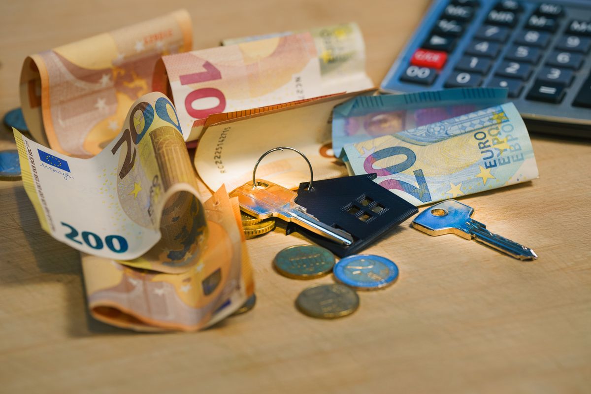 Euro banknotes and coins with house keys on a table symbolize finance and real estate. Euro banknotes and coins with house keys on a table symbolize finance and real estate.