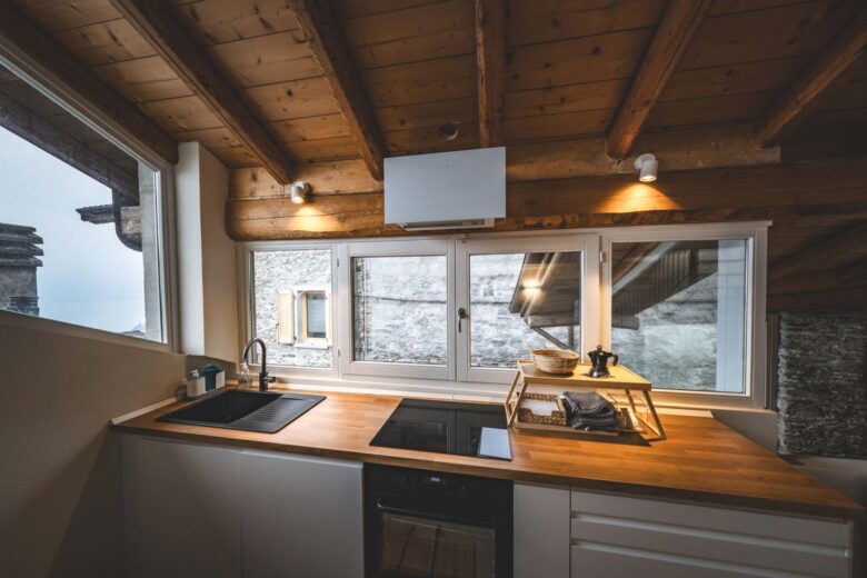 A stylish modern kitchen with wooden beams and natural light in Calozzo, Italy.