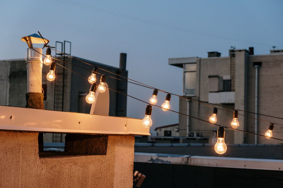 Warm string lights on a rooftop create a cozy atmosphere at twilight in an urban setting. Warm string lights on a rooftop create a cozy atmosphere at twilight in an urban setting.