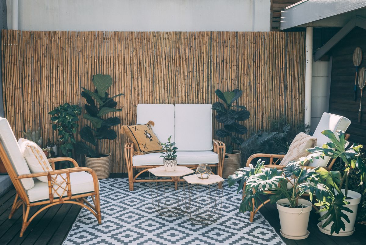 Serene outdoor patio featuring rattan furniture, potted plants, and bamboo decor. Serene outdoor patio featuring rattan furniture, potted plants, and bamboo decor.