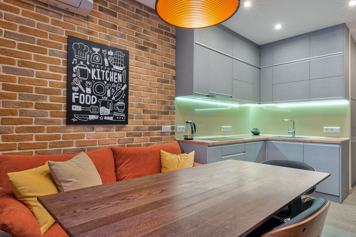 A modern kitchen with brick wall, cozy seating, and stylish lighting.