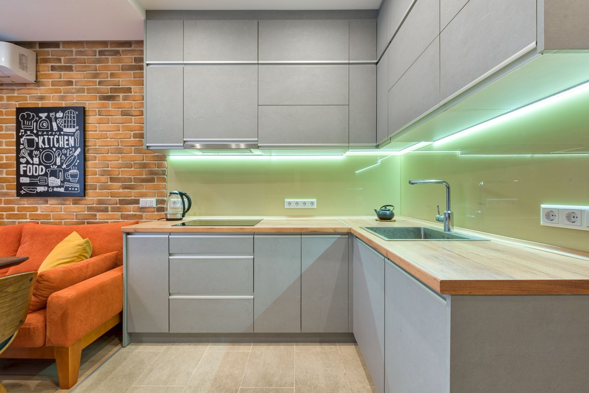Sleek kitchen with gray cabinets, brick wall, and stylish lighting for a cozy atmosphere.
