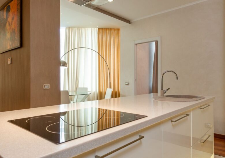 Built in stove and sink with chrome faucet on counter in modern kitchen with dining area in spacious apartment