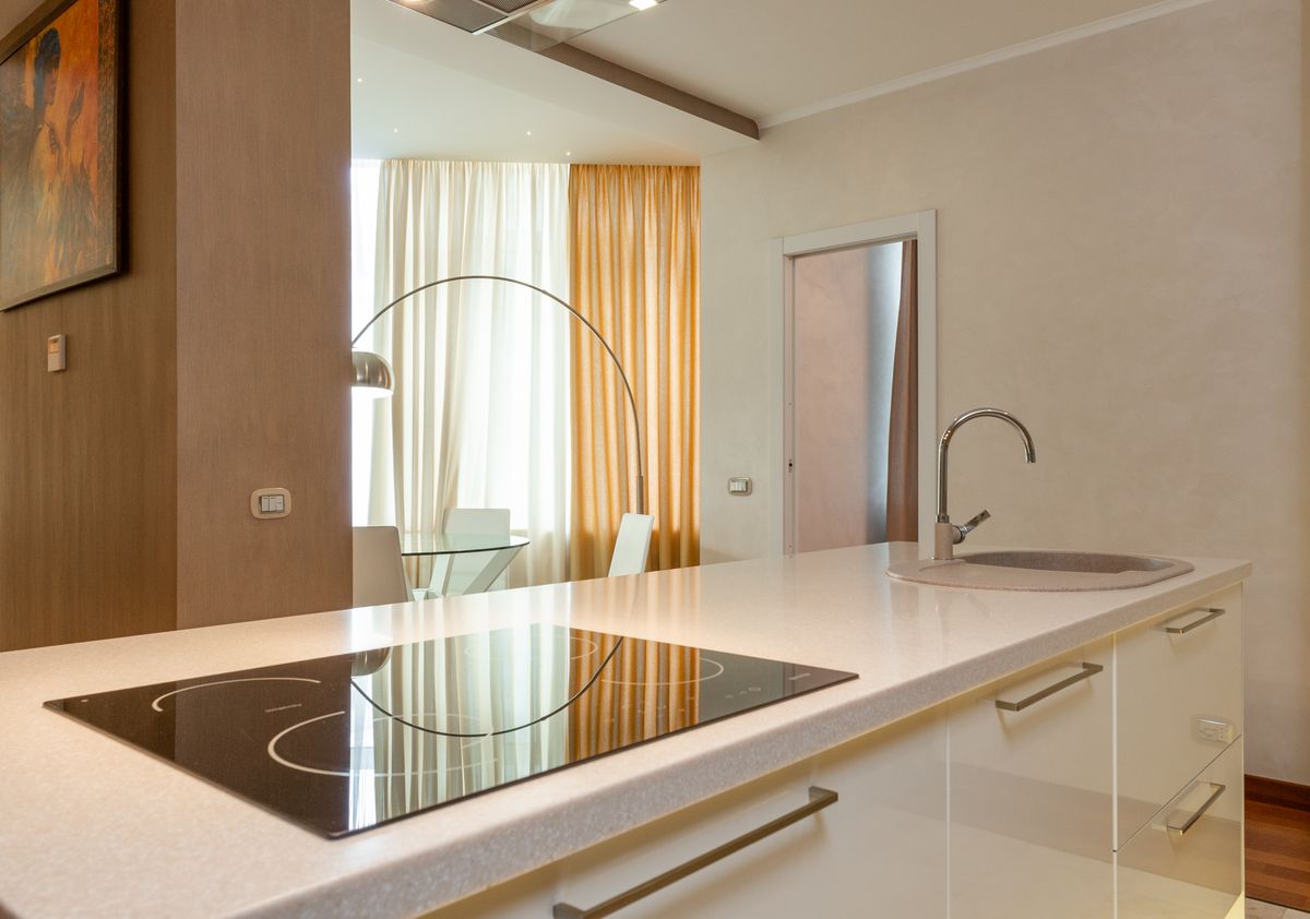 Built in stove and sink with chrome faucet on counter in modern kitchen with dining area in spacious apartment Built in stove and sink with chrome faucet on counter in modern kitchen with dining area in spacious apartment