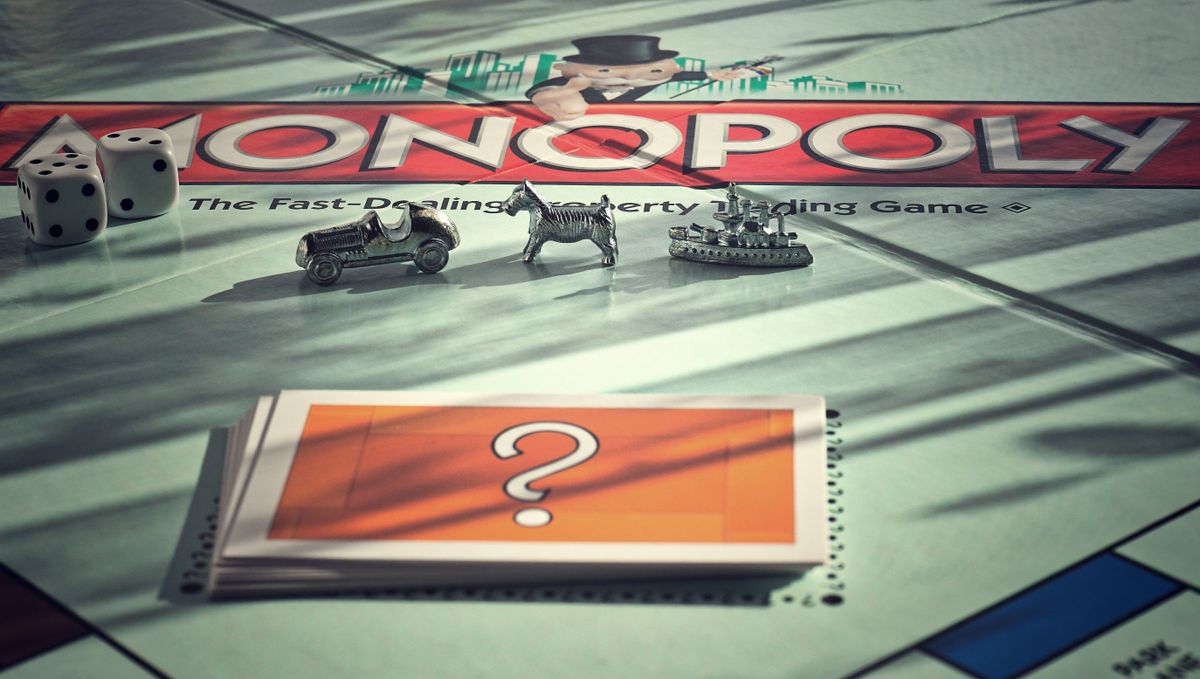 Close-up of Monopoly board game with metal tokens and dice in warm light. Close-up of Monopoly board game with metal tokens and dice in warm light.