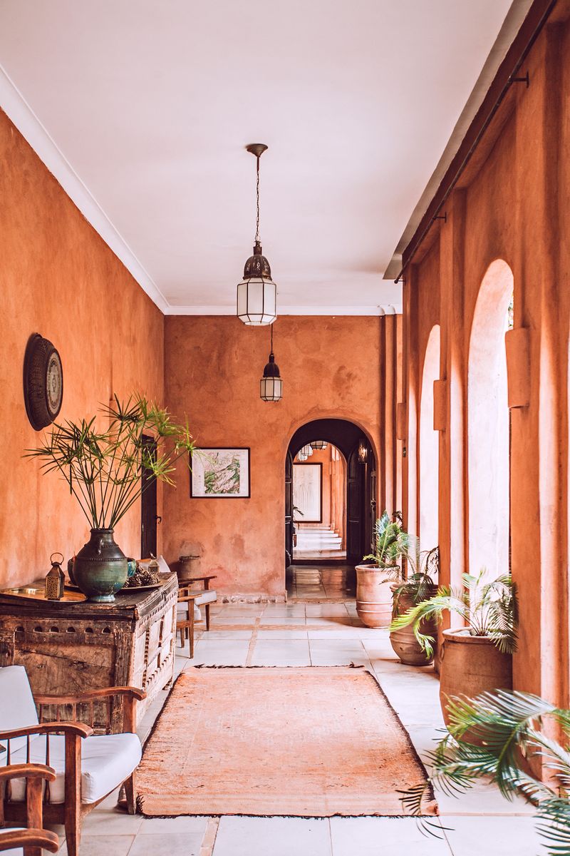 Stylish interior of spacious mansion porch in rustic style with arched doorways and big potted plants on sunny day Stylish interior of spacious mansion porch in rustic style with arched doorways and big potted plants on sunny day