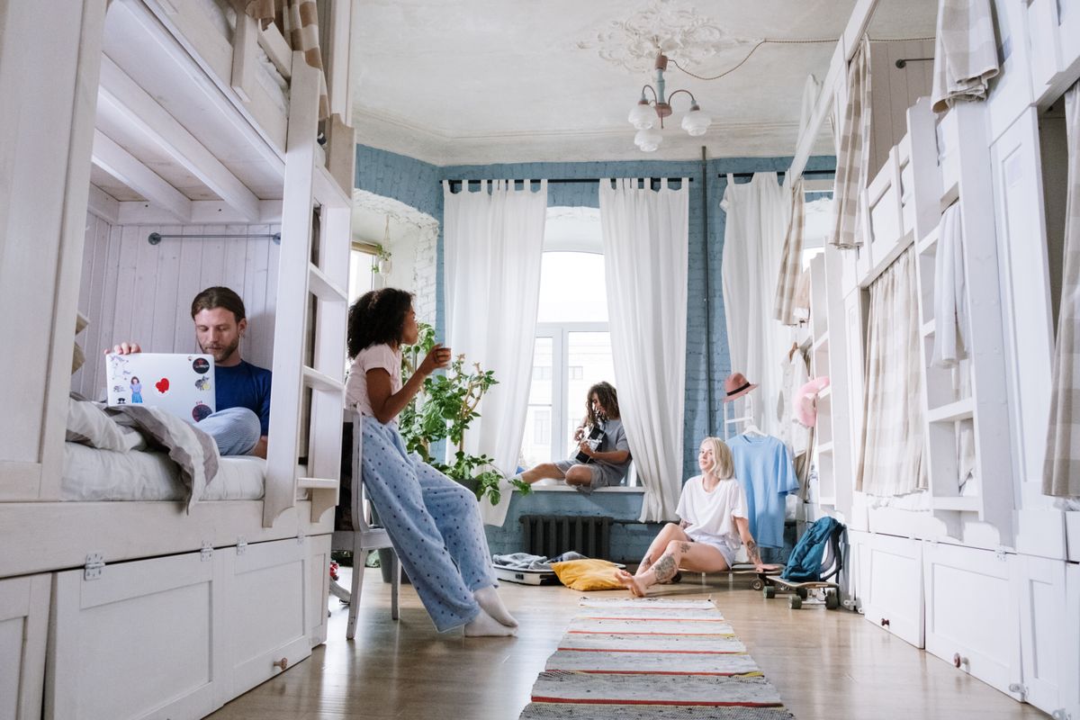 A cozy dorm room where friends relax, chat, play guitar, and use laptops together. A casual hangout environment. A cozy dorm room where friends relax, chat, play guitar, and use laptops together. A casual hangout environment.