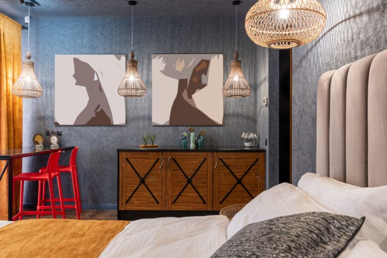 Cushions on bed against cabinet with decoration under artworks illuminated by shiny lamps at home