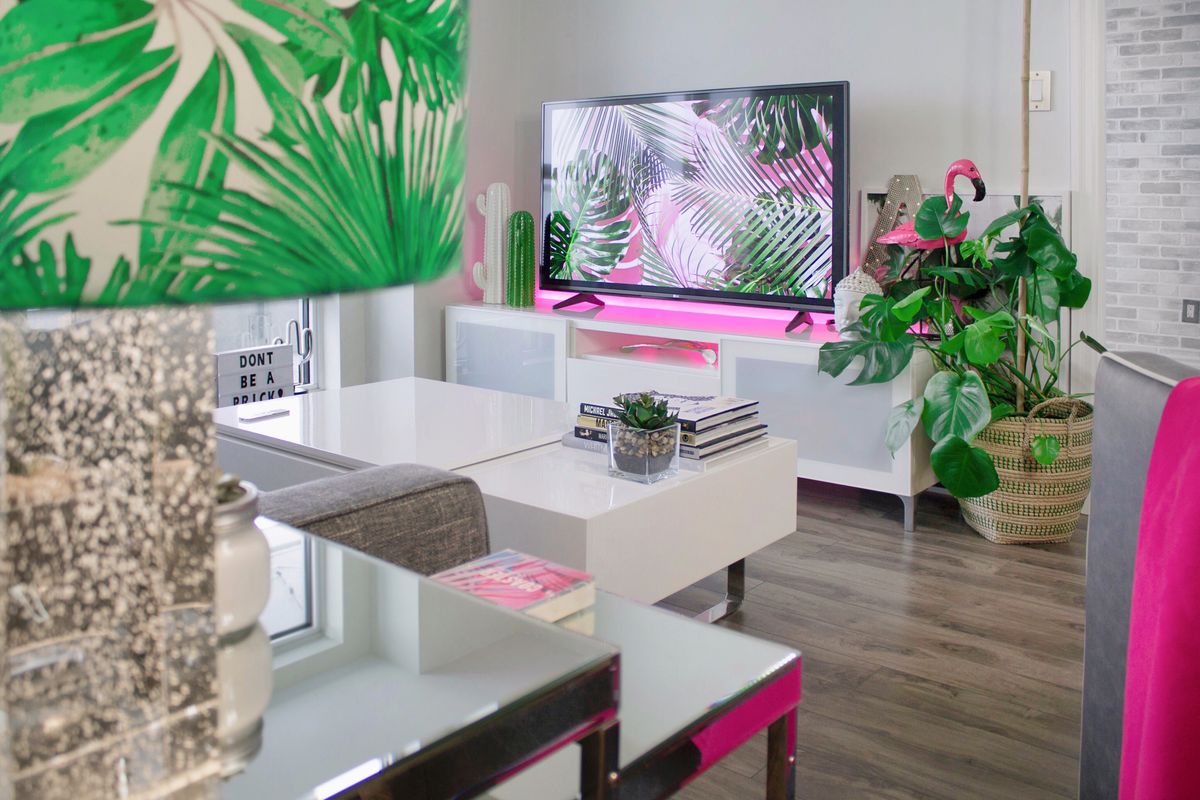 A stylish living room featuring tropical-themed decor, plants, and a modern TV setup. A stylish living room featuring tropical-themed decor, plants, and a modern TV setup.
