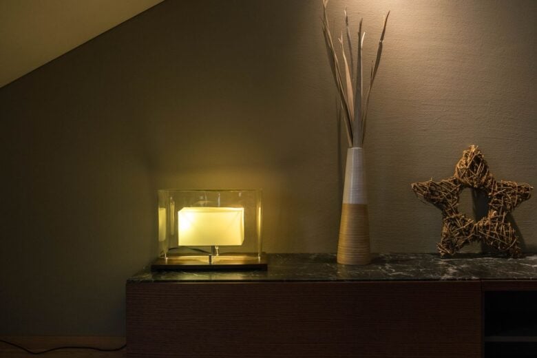 Elegant interior setup featuring a modern lamp, a tall vase with twigs, and a decorative star on a shelf.