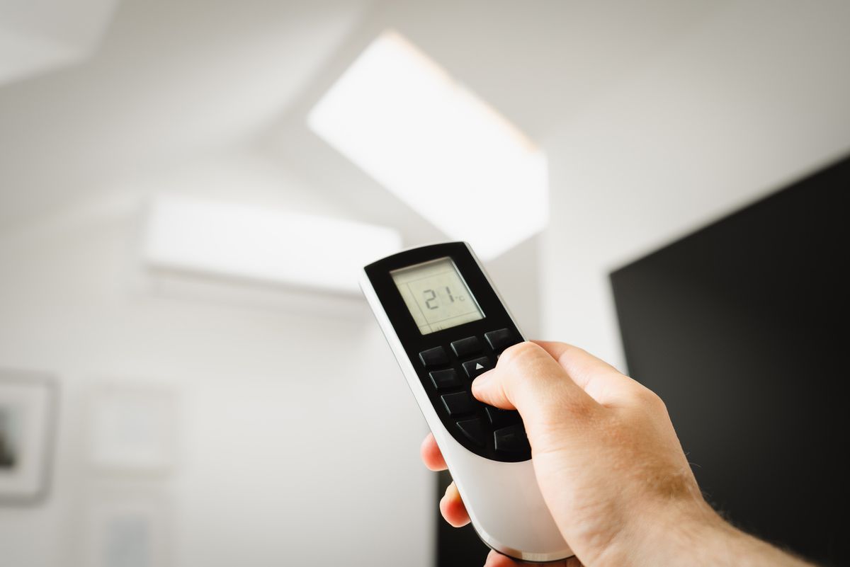Close-up of a man using a remote to control air conditioning indoors. Close-up of a man using a remote to control air conditioning indoors.