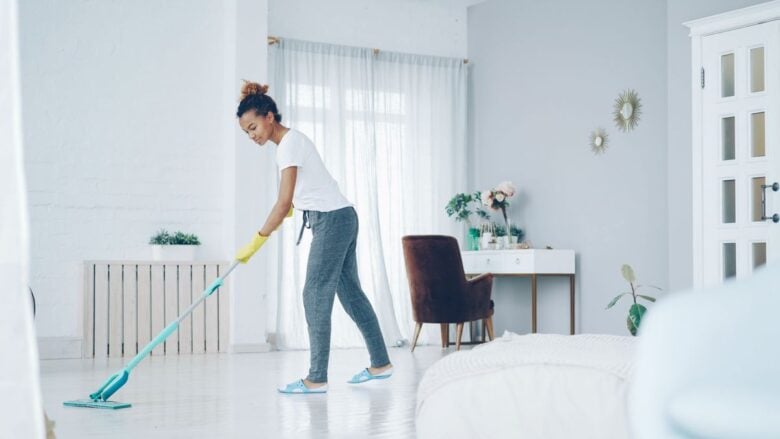 A woman cleaning a bright, modern living room with a mop, creating a clean, welcoming space.