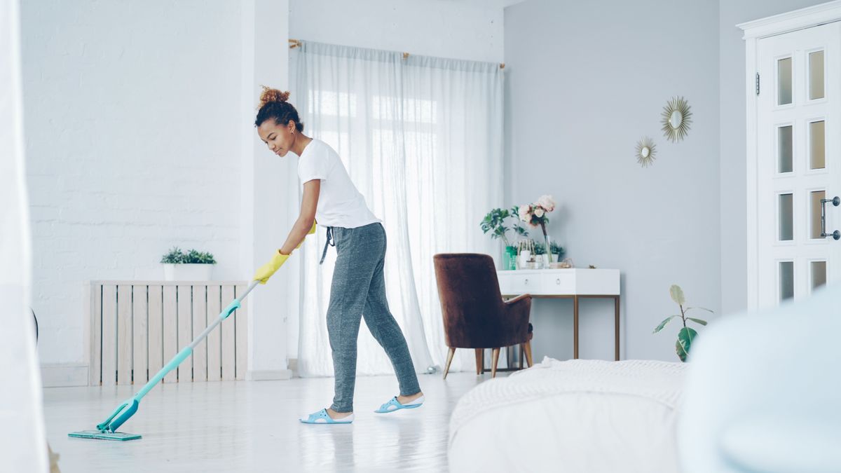 A woman cleaning a bright, modern living room with a mop, creating a clean, welcoming space. A woman cleaning a bright, modern living room with a mop, creating a clean, welcoming space.