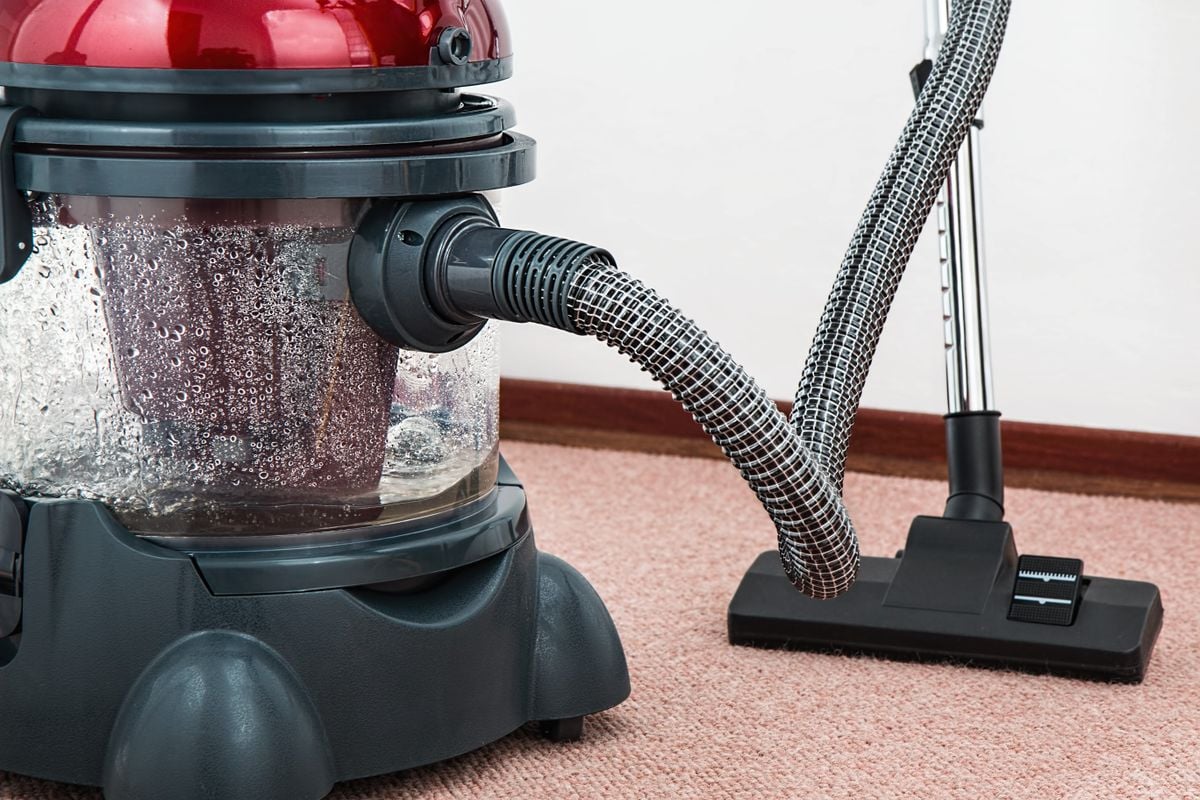 Close-up of a modern vacuum cleaner with water filtration on carpet floor indoors. Close-up of a modern vacuum cleaner with water filtration on carpet floor indoors.