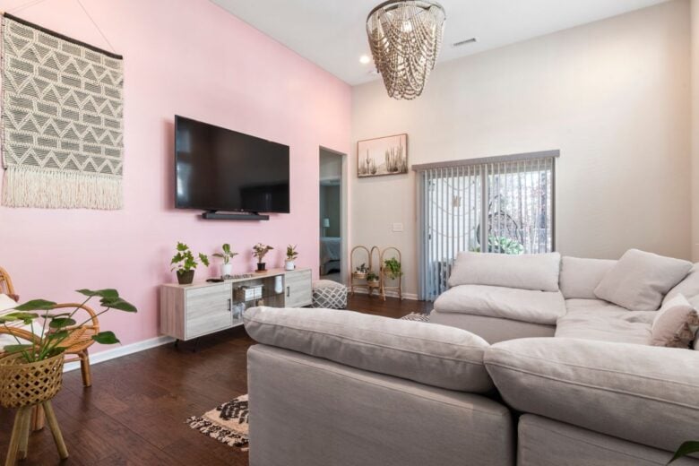 Chic living room featuring a pink accent wall, comfortable couch, and contemporary decor elements.
