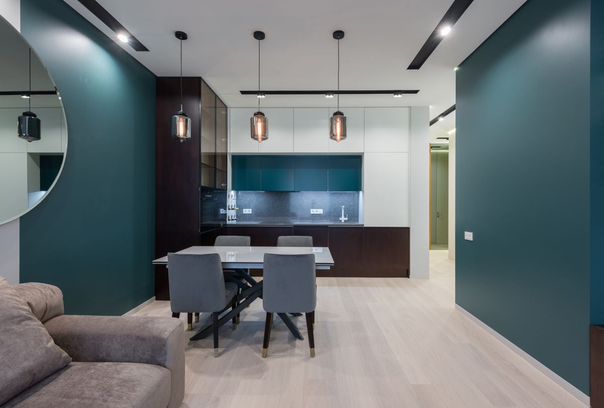 Dining table with chairs in kitchen near comfy sofa in modern studio apartment with creative design Dining table with chairs in kitchen near comfy sofa in modern studio apartment with creative design