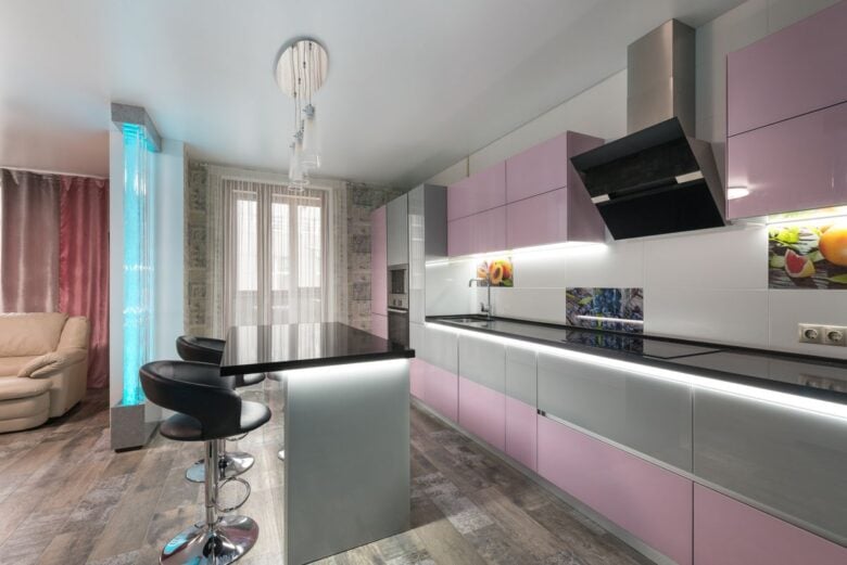 Table with chairs placed near colorful cupboards with modern appliances in stylish kitchen with decorative bubble wall in spacious apartment