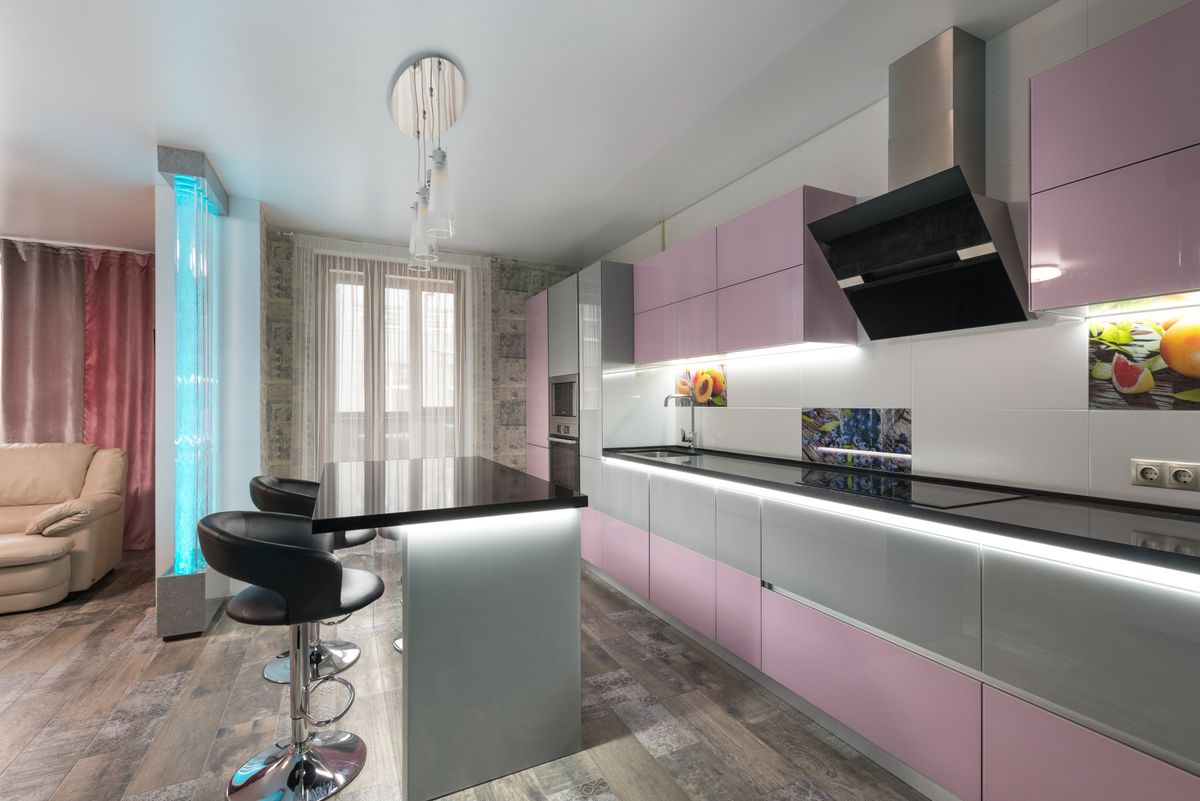 Table with chairs placed near colorful cupboards with modern appliances in stylish kitchen with decorative bubble wall in spacious apartment Table with chairs placed near colorful cupboards with modern appliances in stylish kitchen with decorative bubble wall in spacious apartment