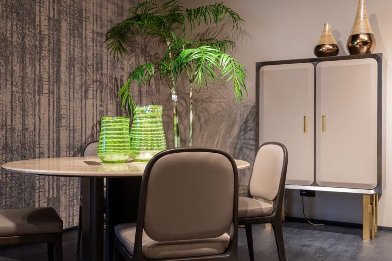 Trendy contemporary interior design of dining room with round table cozy chairs and stylish cupboard decorated with creative vases