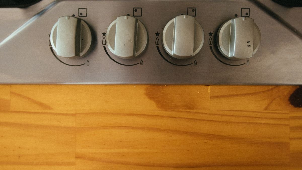 A close-up view of modern stove control knobs on a wooden countertop. A close-up view of modern stove control knobs on a wooden countertop.