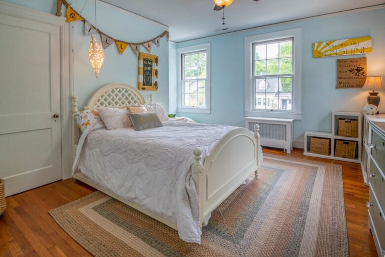 Cozy bedroom with elegant vintage decor and ample natural light from large windows.