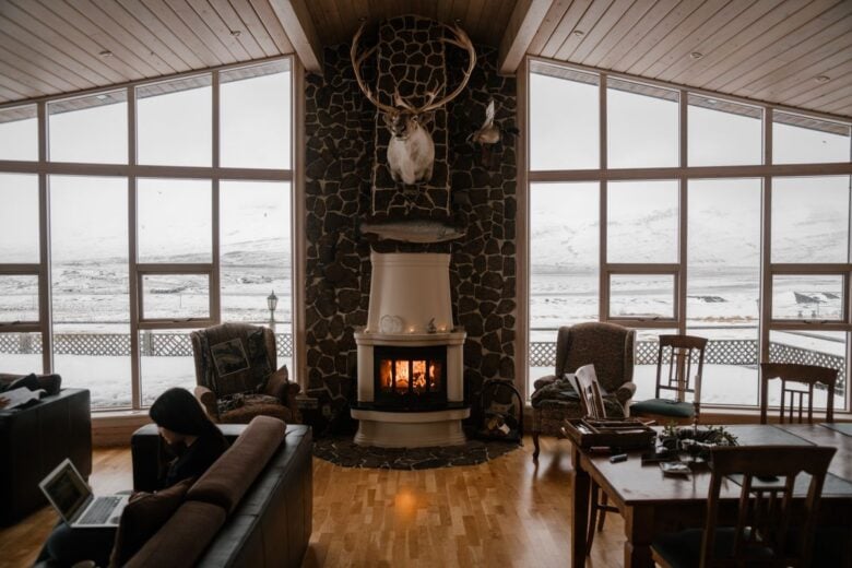 Warm and inviting living room with a fireplace and large windows overlooking snow-covered mountains.