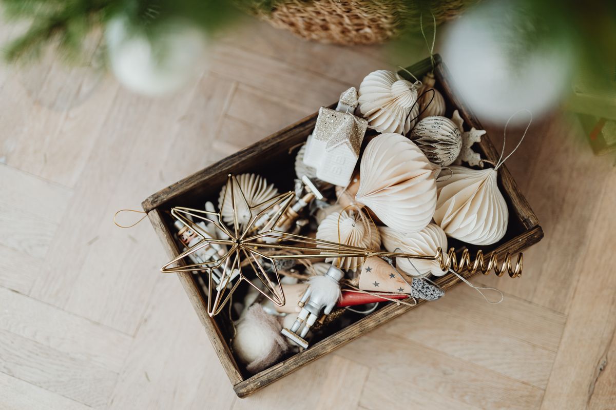 Aerial view of Christmas ornaments in a wooden box on a wooden floor.